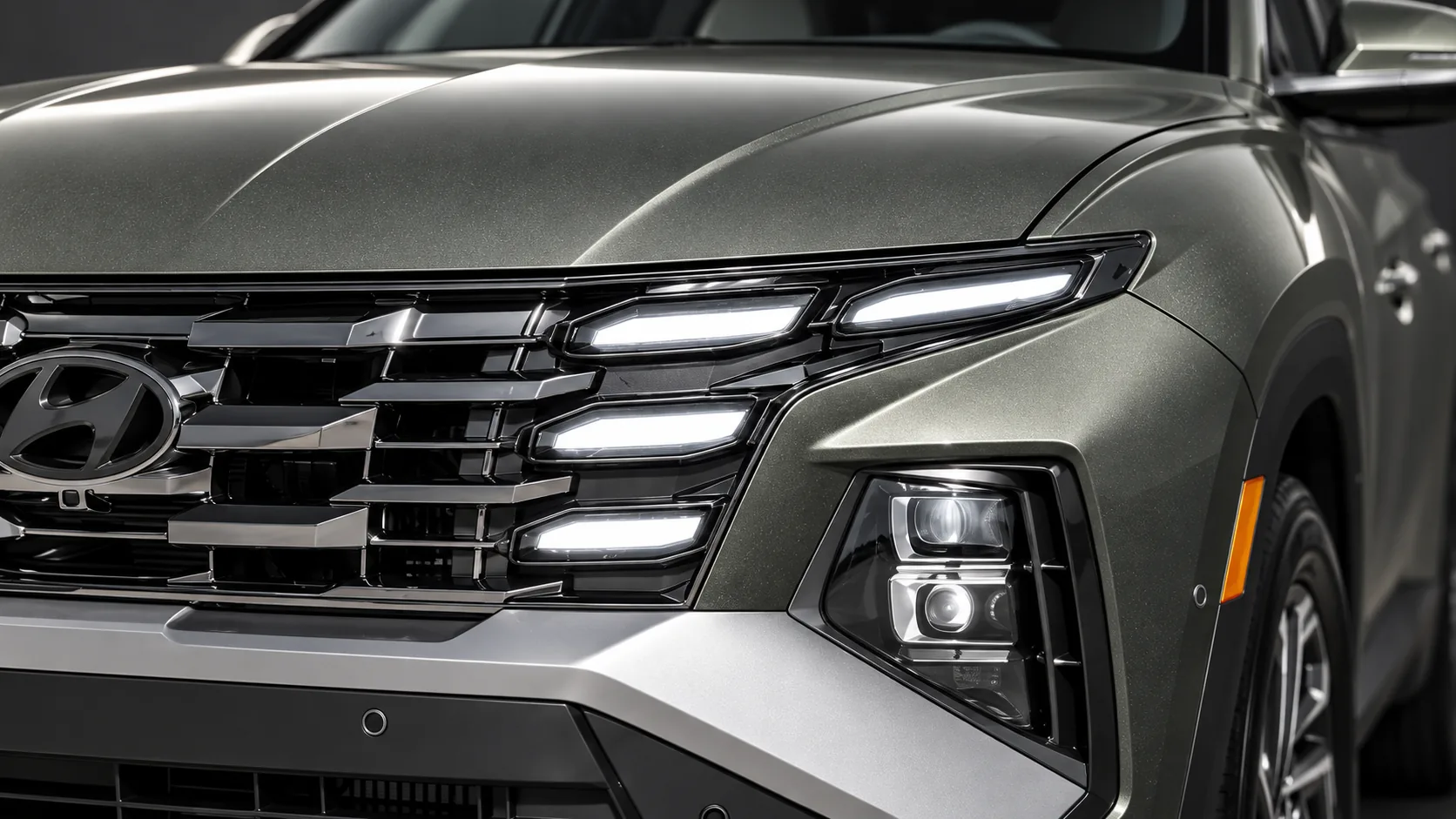 Close-up of the Tucson’s grille, LED lamps and metallic hood under precise studio lighting.