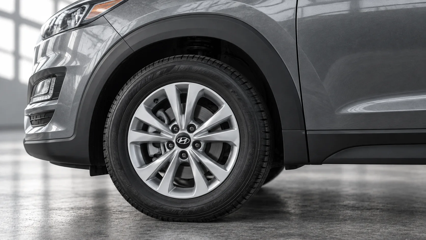 Close-up of a used Tucson’s factory alloy wheel, tyre and grey front fender.